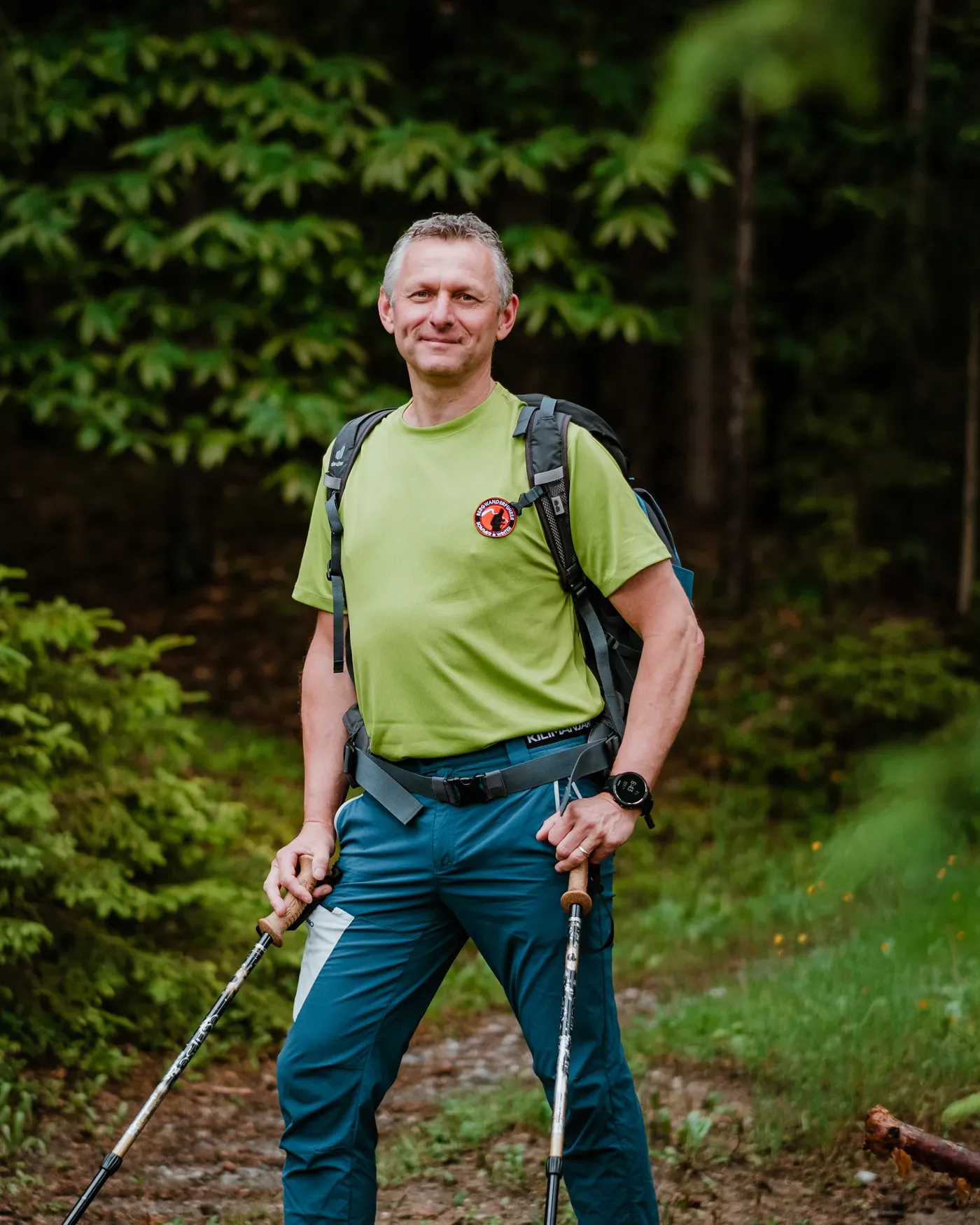 Andreas Kohlbacher mit Rucksack und Wanderstöcken auf einem Waldweg in der Weststeiermark