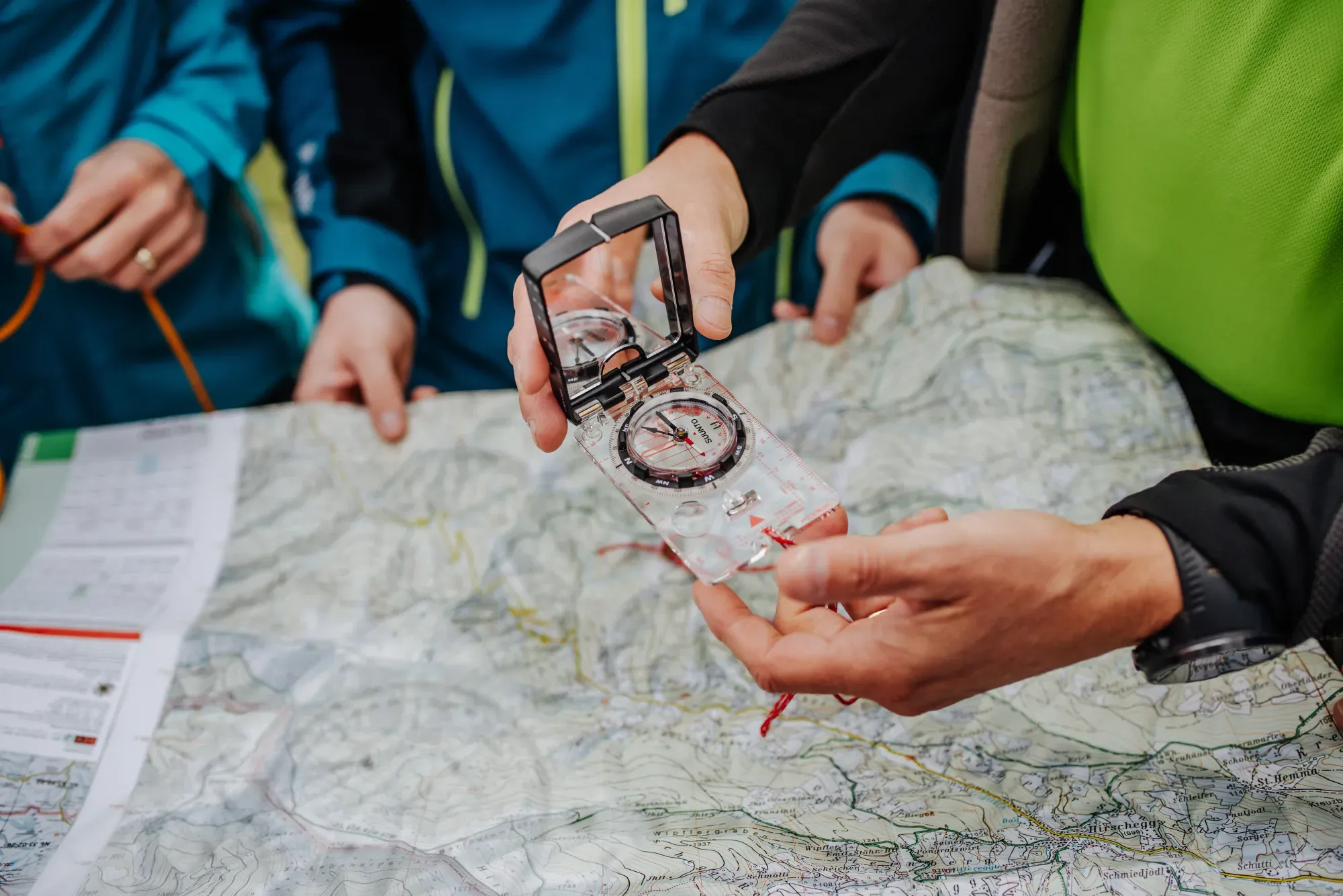 Andreas Kohlbacher zeigt einer Gruppe die Orientierung mit Kompass und Wanderkarte