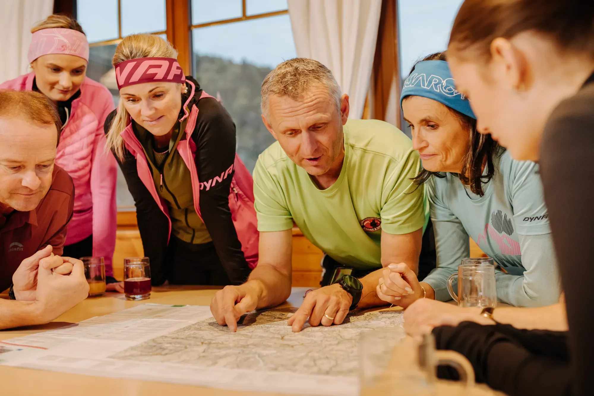 Andreas Kohlbacher bespricht mit einer Gruppe die Route über einer Landkarte am Tisch