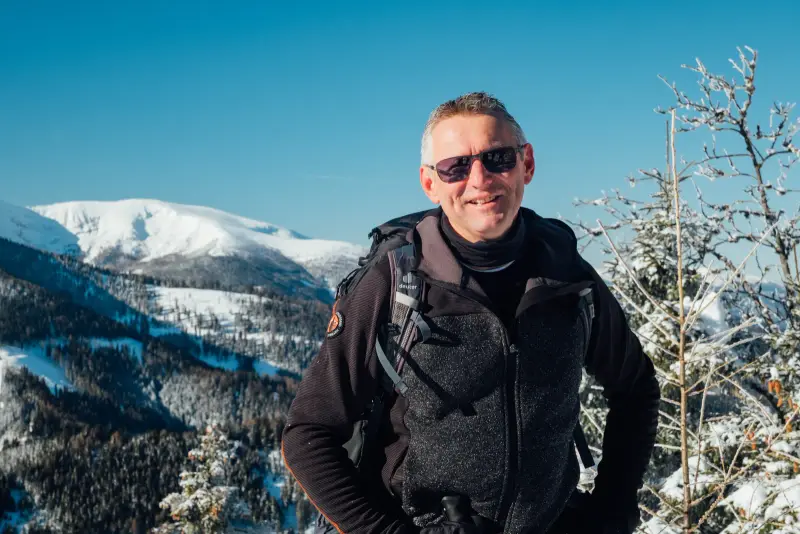 Andreas Kohlbacher auf einer Winterwanderung, verschneite Berge im Hintergrund